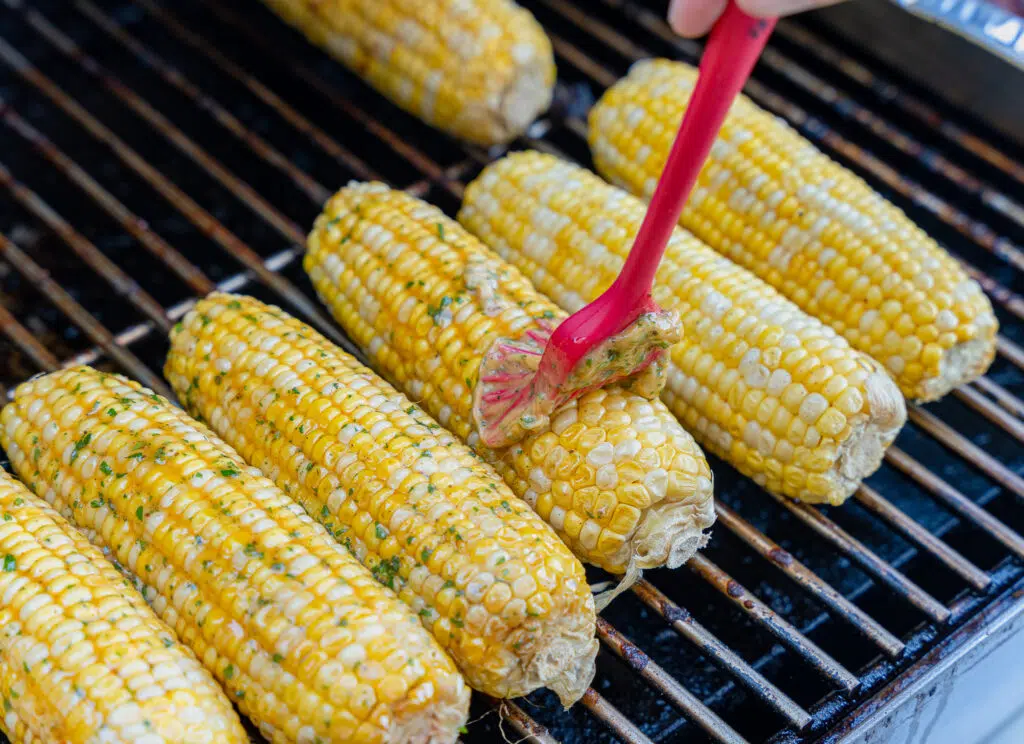 brushing corn on the cob with honey miso butter
