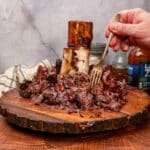 shredded smoked beef shank on a cutting board with bbq sauce