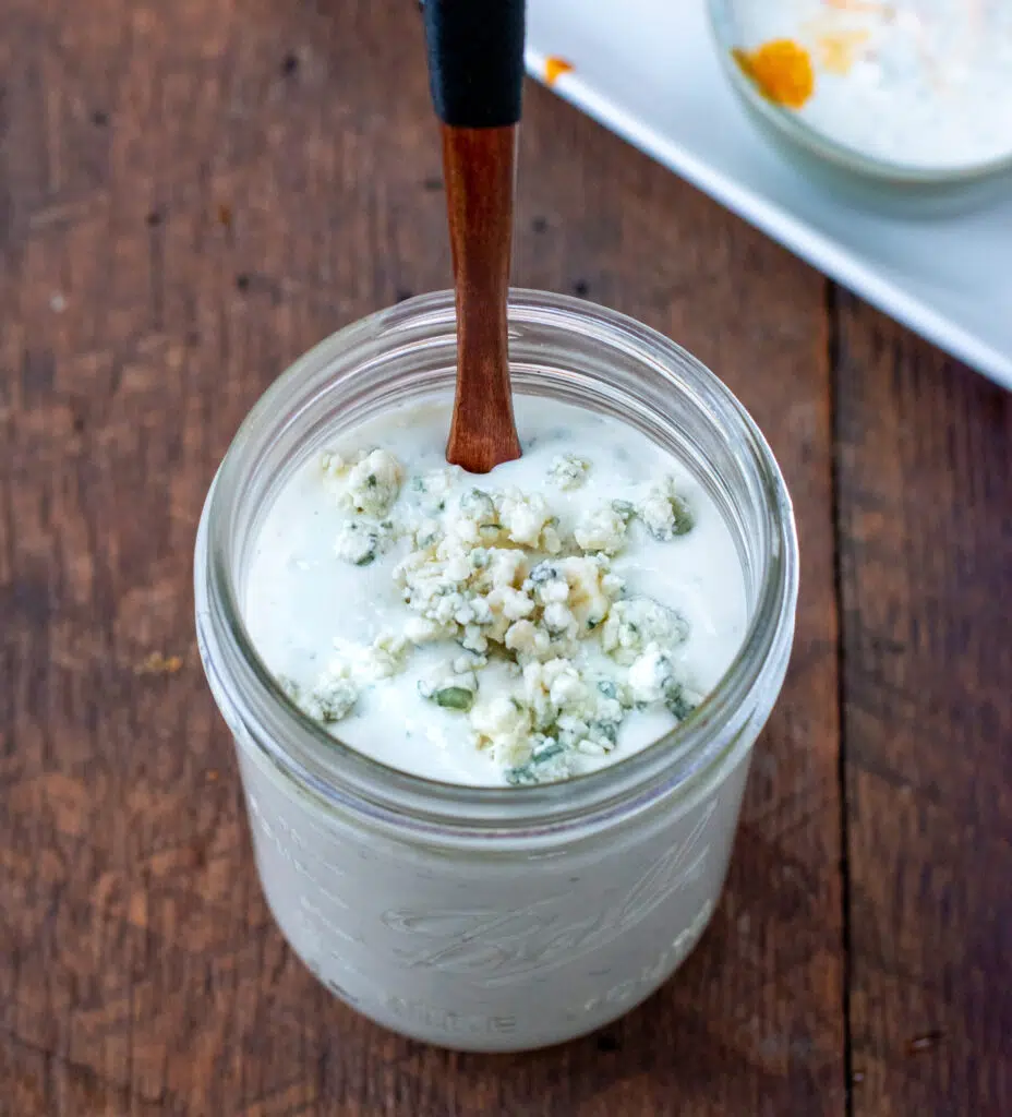 spoon in a jar of chunky blue cheese dressing