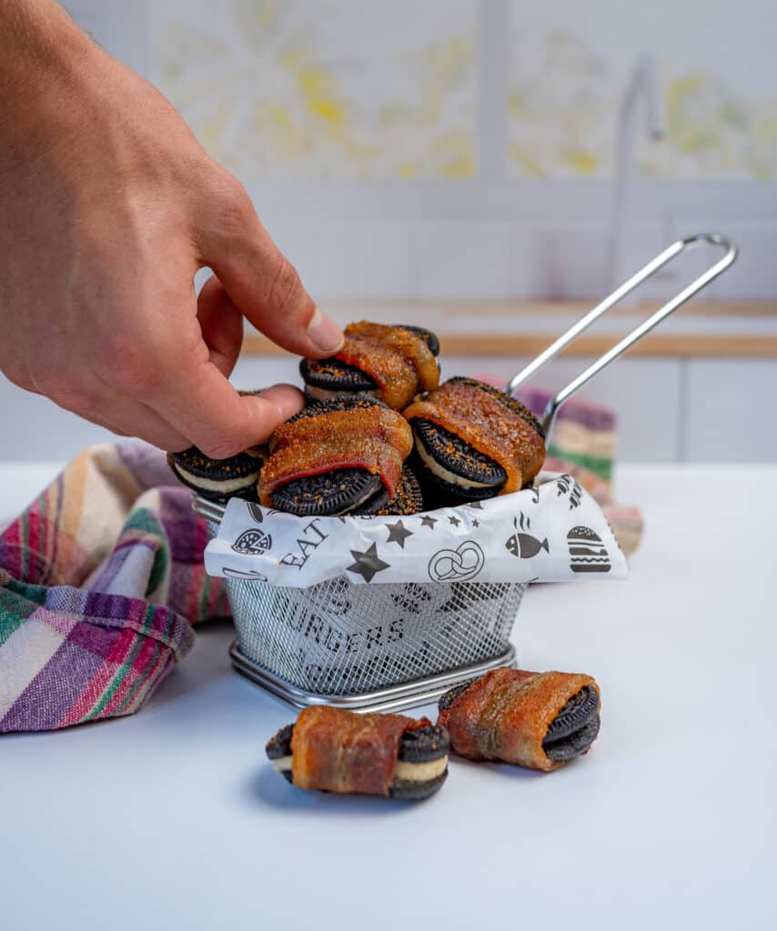 grabbing bacon wrapped Oreos out of a fry basket lined with deli paper