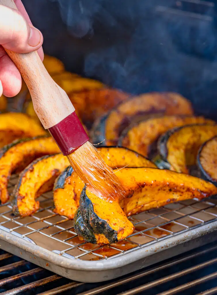 brushing sauce on the smoked acorn squash still on the pellet grill