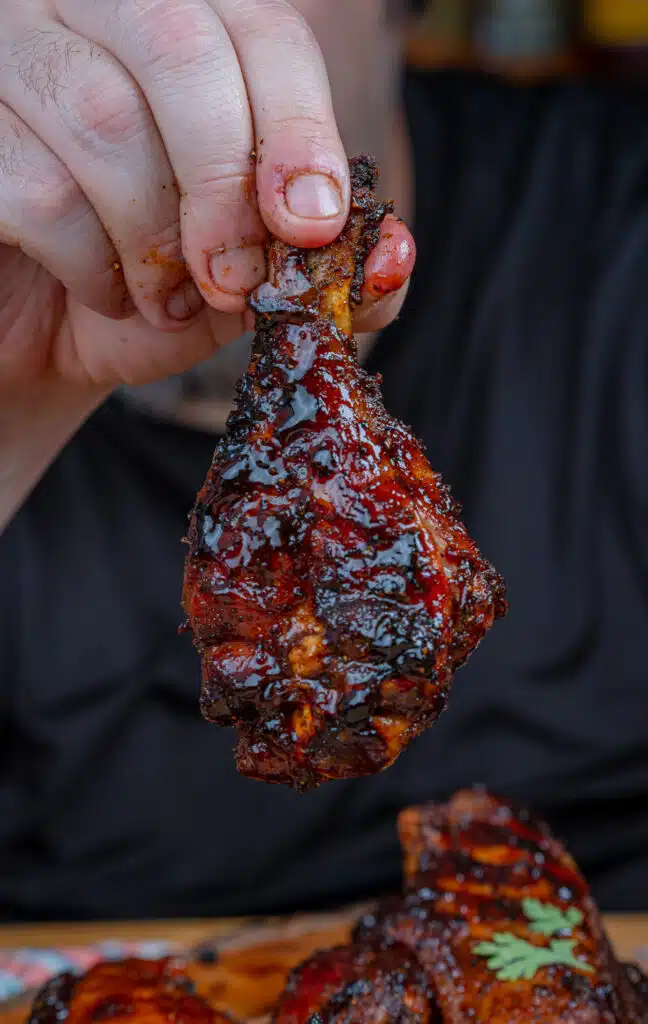 smoked turkey drumstick wing in my hands covered in bbq sauce