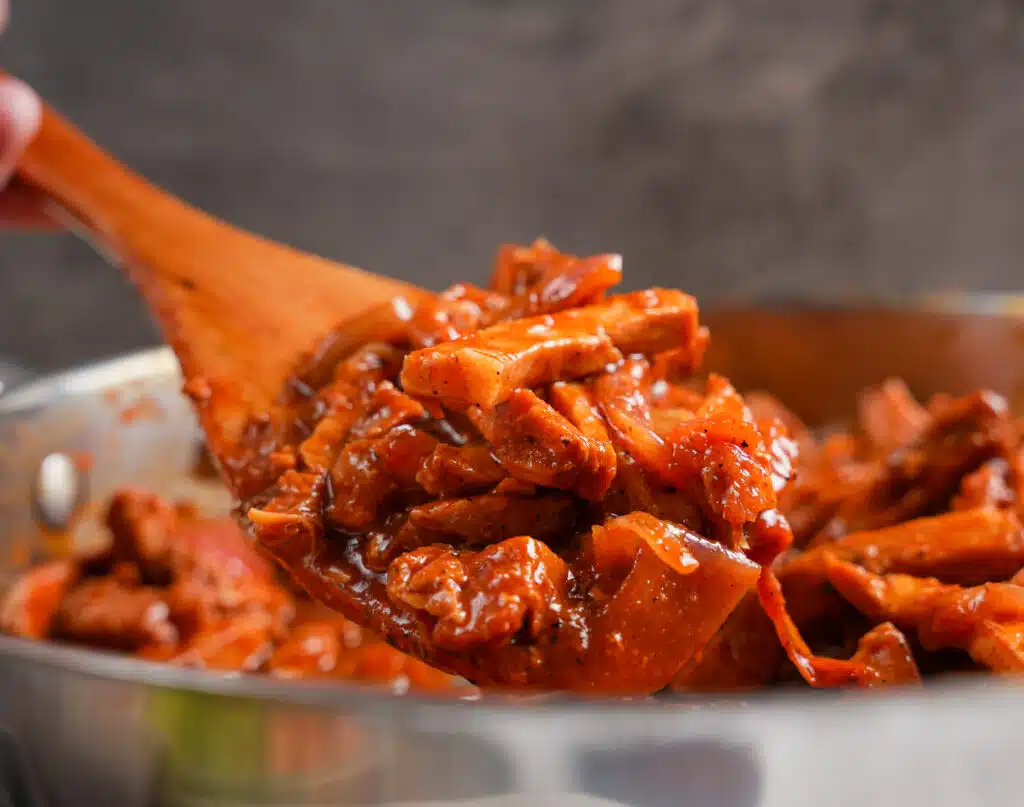 scoop of pork tenderloin simmered in a red sauce