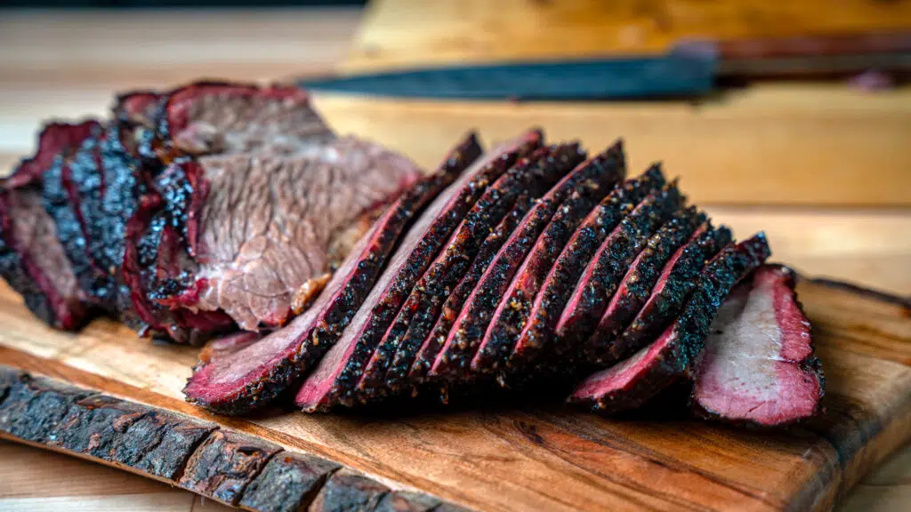 sliced beef brisket hand carved on a cutting board
