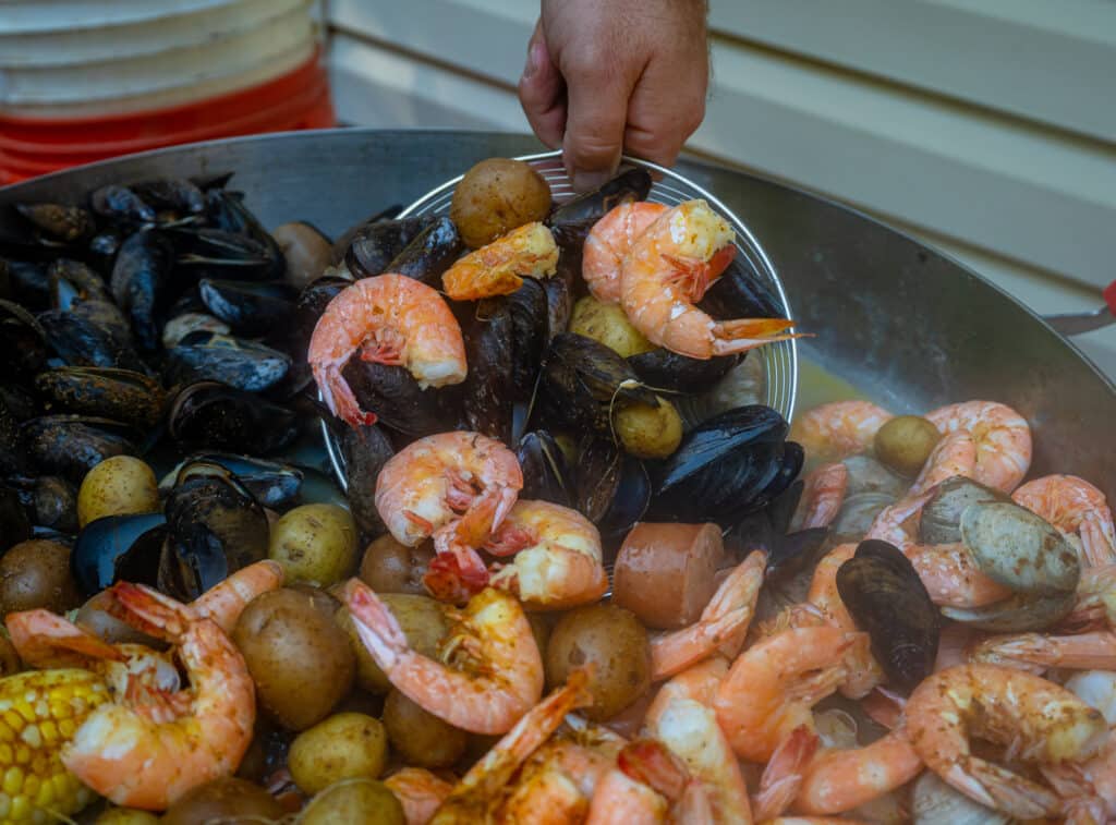 scooping mussels and shrimp out of a pot