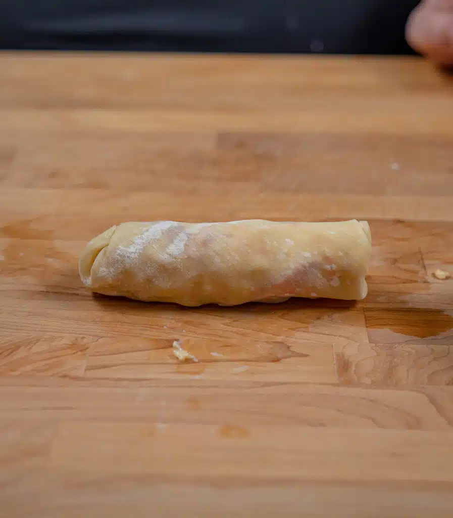 uncooked lobster egg roll rolled up on a cutting  board