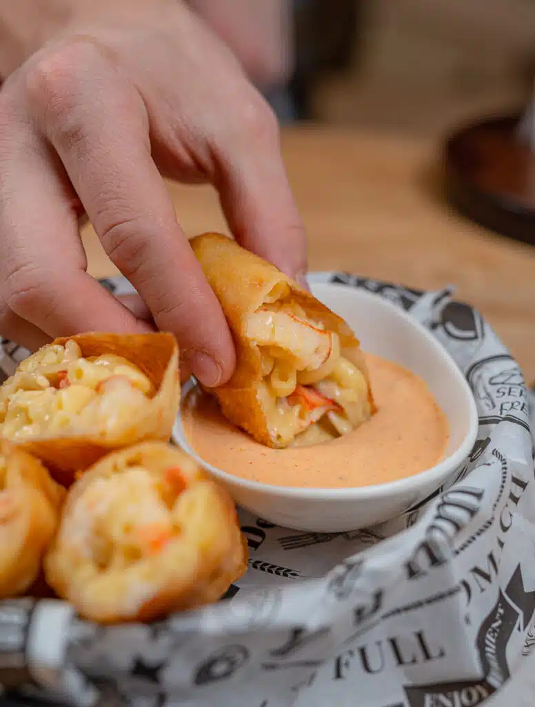 dipping lobster Mac and cheese egg roll into old bay dipping sauce