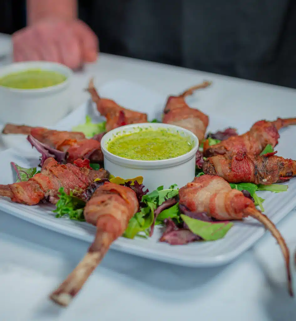 Bacon Wrapped Lamb Chops on a plate with dipping sauce