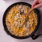 using a wooden spoon to scoop the sausage casserole with egg noodles