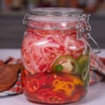 pickled onions and jalapeños in a jar on a countertop