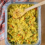 Rice Pilaf in a foil pan with a wooden spoon