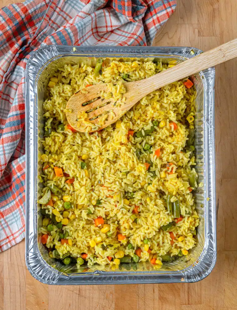 Rice Pilaf in a foil pan with a wooden spoon
