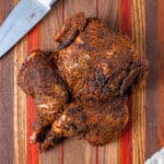 Spatchcock chicken on a cutting board with a knife