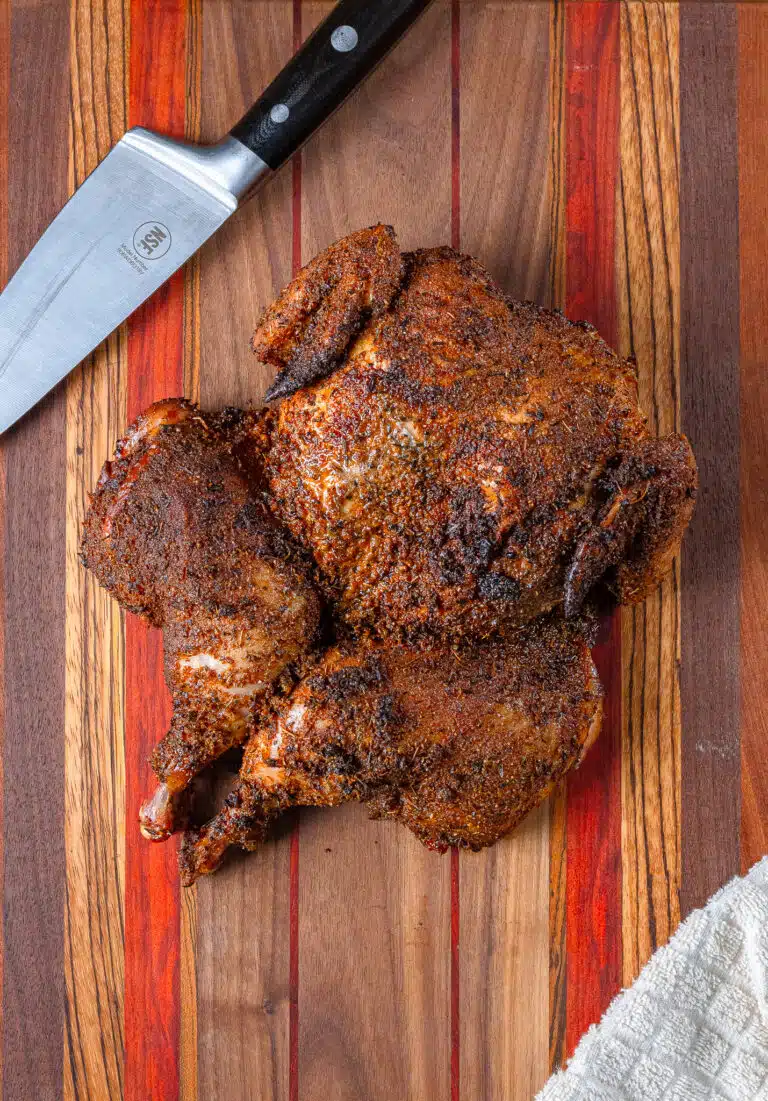 Spatchcock chicken on a cutting board with a knife