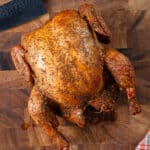Whole smoked chicken resting on a cutting board