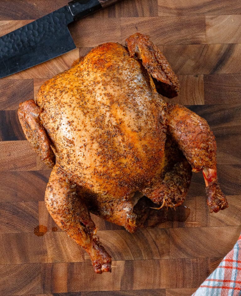 Whole smoked chicken resting on a cutting board