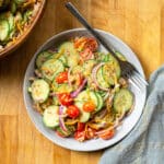 spicy cucumber salad served in a white bowl with a fork laid to the side