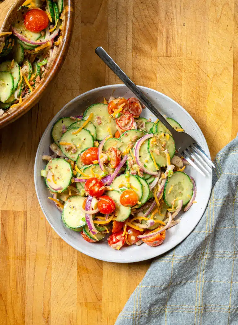 spicy cucumber salad served in a white bowl with a fork laid to the side