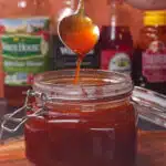 Peach bourbon bbq sauce dripping off of a spoon into a jar