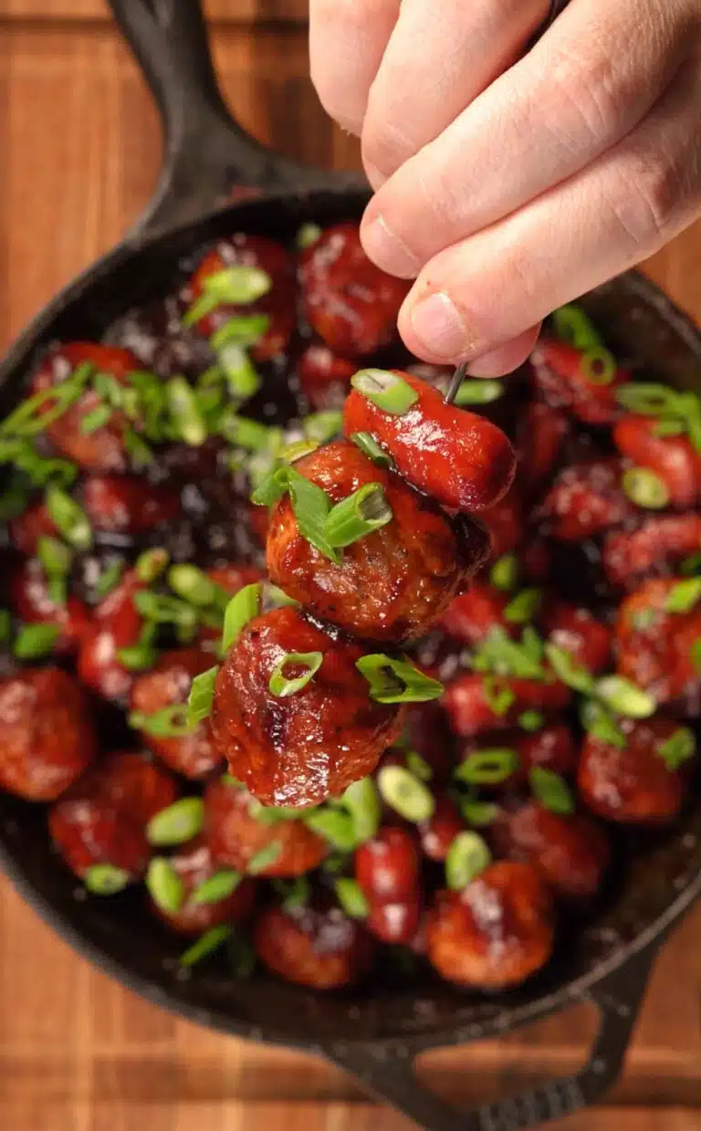 cast iron pan with meatballs and sausages in bbq sauce