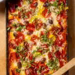 cast iron pan with pizza beans topped with pepperoni, cheese olives and other toppings