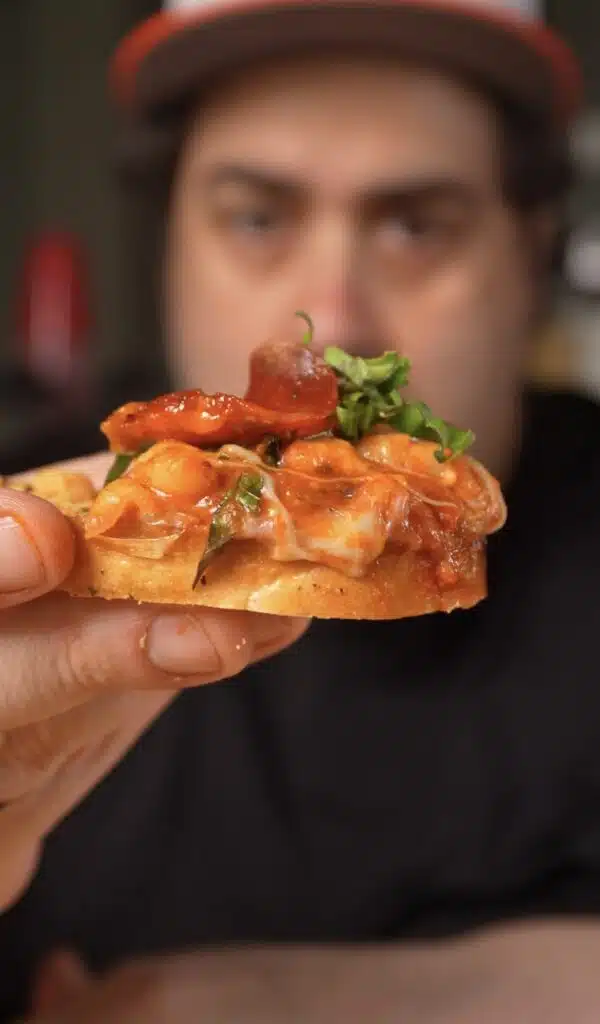holding a crostini out I n front loaded with pizza beans