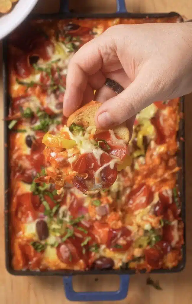 holding a slice of Italian bread over the pizza beans