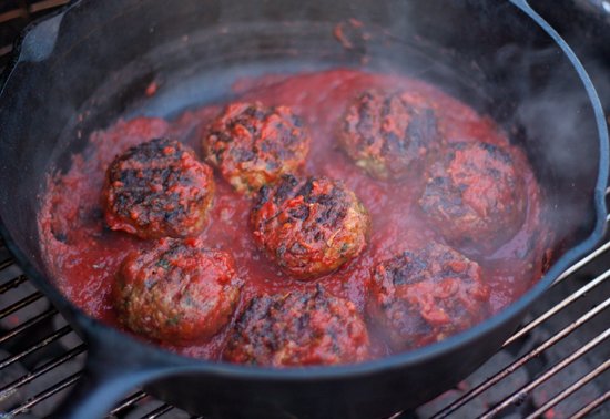 Grilled Meatballs simmering in a sauce in a cast iron skillet