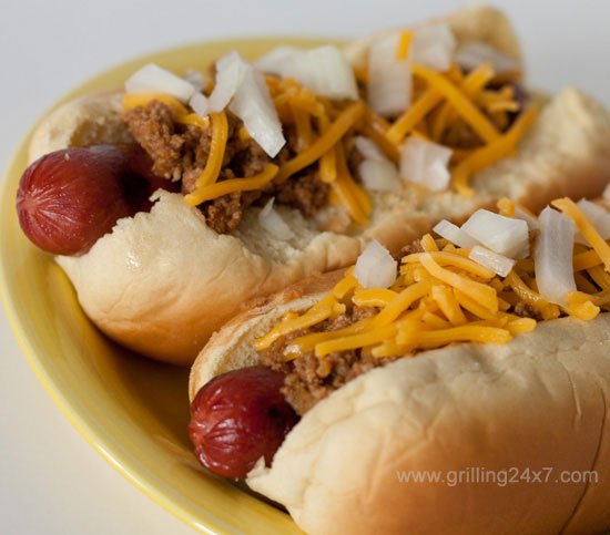 close up of Chili Dogs with Chili Sauce, onions and cheese on a plate
