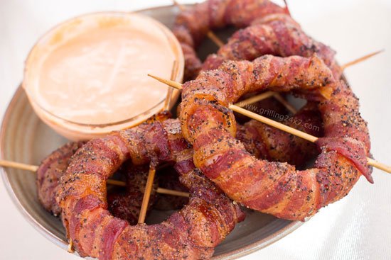 Smoked Bacon Wrapped Onion Rings on plate with Spicy Sriracha Mayo Dipping Sauce on side